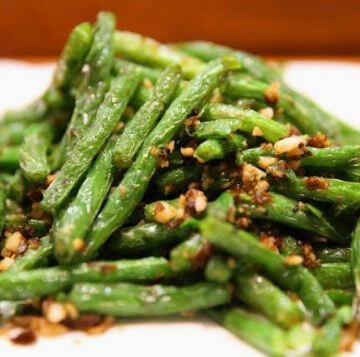 Blistered, vibrant green string beans stir-fried with minced garlic and aromatic spices.