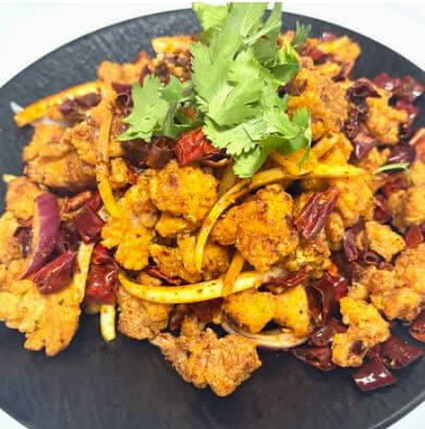 Crispy, golden-fried chicken cubes buried in a vibrant bed of red Sichuan chilis and topped with cilantro.
