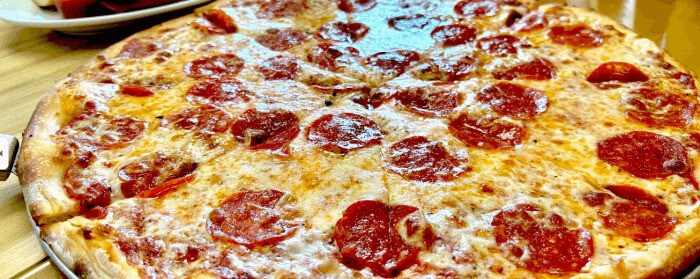 Crispy thin crust pizza topped with rich tomato sauce, mozzarella cheese, and evenly layered pepperoni slices, hot out of the oven.