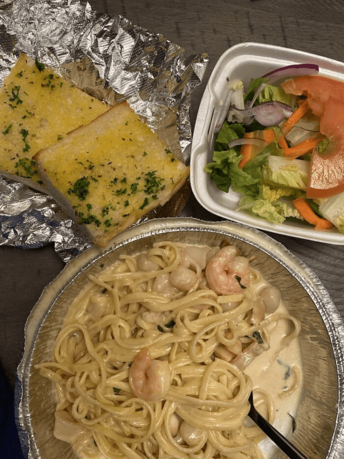 Penne pasta drenched in rich marinara, topped with jumbo shrimp and melted mozzarella, served on a rustic ceramic plate.