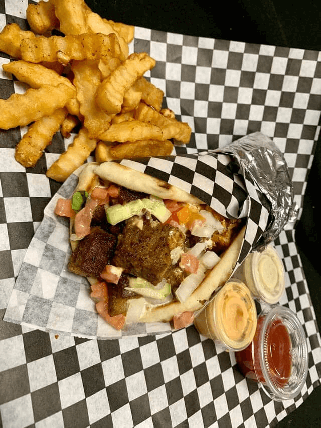 A warm pita filled with gyro chunks, vegetables, and white and house sauces.