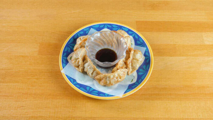 Golden brown gyoza on blue ceramic plate