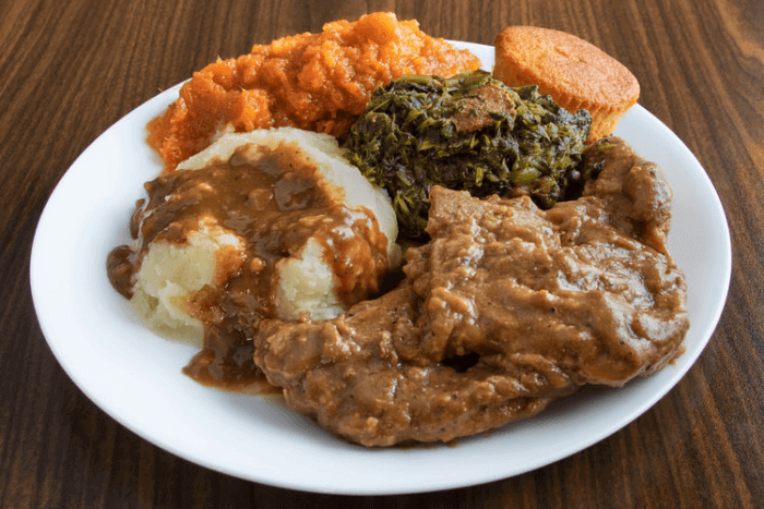 Brown-gravy porkchops on mashed potatoes with a side of greens.