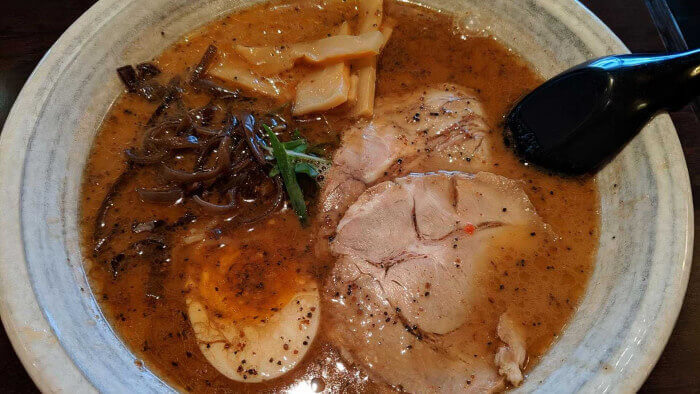 Black garlic ramen with chashu pork, soft egg, and bamboo in a dark broth