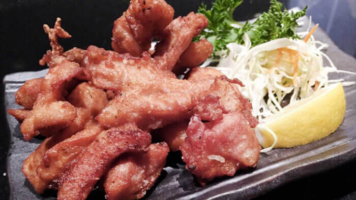 Golden crispy Japanese fried chicken with dipping sauce on a ceramic plate