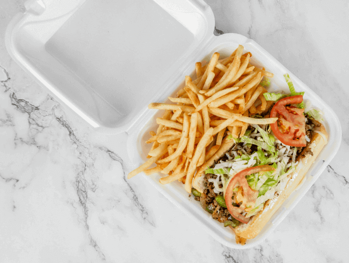 Philly cheesesteak sandwich with grilled onions, bell peppers, mushrooms, and cheese, served with crispy fries
