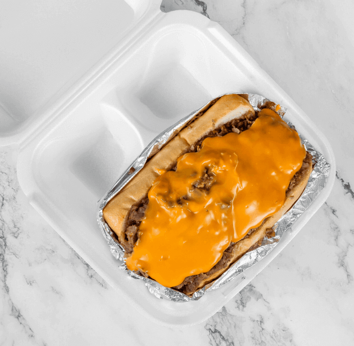 Classic Philly cheesesteak sandwich with grilled onions and melted Cheese Wiz, served with a side of crispy golden fries