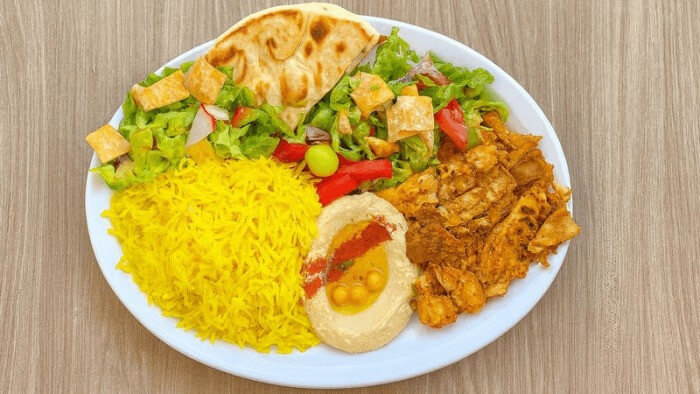 Chicken shawarma with basmati rice, dip, salad, and grilled pita.